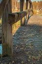 Close-up of an old mossy wooden bridge over a river, brook, stream or creek. Old worn wood is covered with yellow and green moss.