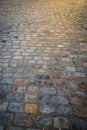 Close up of old multicoloured coblestones on street with sun flare shining down on them from above.