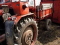 Close-up of old neglected dark red tractor with rubber dirty wheels