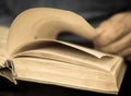 Close-up of an old open book being held by the hands of an elderly man. Book wisdom and knowledge theme. selective focus, shallow Royalty Free Stock Photo