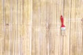 Old paint  brush with red handle hang on light brown bamboo wood background Royalty Free Stock Photo