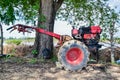 Close up of the old red tiller tractor or walking tractor parked under the tree in the fields at countryside, Thailand Royalty Free Stock Photo