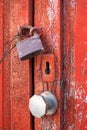 Close up of an old red wooden door closed with padlock and iron wire. Rustic country style as per spanish tradition Royalty Free Stock Photo