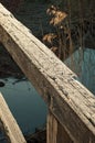 Close-up of an old rustic wooden bridge railing, rail, handrail or banister. Old worn wood in the sunlight. Bridge going over a