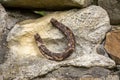 Close-up of an old rusty horseshoe propped on a big stone. Royalty Free Stock Photo