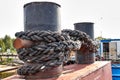 Close up of an old rusty metal bollard for mooring ships with a metal cable. Rusty metal chain. Royalty Free Stock Photo