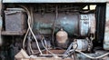 Close-up on an old rusty tractor or truck engine with a battery and oil drips during repair in a workshop. Auto service industry