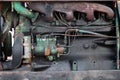 Close-up on an old rusty tractor or truck engine with a battery and oil drips during repair in a workshop. Auto service industry