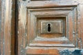 Close-up of the old shabby wooden door of dark brown colour with keyhole. Rustic antique entrance