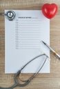 Stethoscope and pen with red heart on empty checklist form Royalty Free Stock Photo