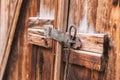 Old simple lock on a wooden door closed with a metal pin rustic latch on an old door made of wood