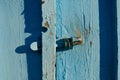 Close-up of an old slightly rusty door handle on a wooden textured door with shabby faded blue paint. Royalty Free Stock Photo