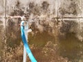 Close up old stainless steel Faucets and blue water rubber hoses on dirty rough cement wall with copy space Royalty Free Stock Photo