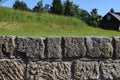 Close-up of old stone wall in the rural landscape. Blurred green meadow with cottage house, trees and blue sky. Europe Royalty Free Stock Photo