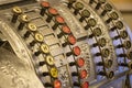 Close-up of an old-time antique brass cash register with buttons for numbers and letters