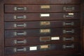 Close up of old vintage vertical wooden cabinet with drawer, handles, plates and blank weathered label for documents. Royalty Free Stock Photo