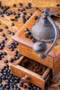 Close-up of old wooden coffee grinder with ground coffee in drawer, and coffee beans on wooden table Royalty Free Stock Photo