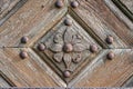Close-up of an old wooden door decorated with carved wooden flowers with corroded and rusty fittings and hinges. Details of wood