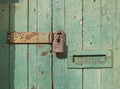 Close up of an old wooden door with green faded paint and a rusty closed padlock and old metal letterbox Royalty Free Stock Photo