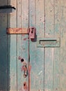 close up of an old wooden door with green faded paint and a rusty closed padlock and old metal letterbox Royalty Free Stock Photo