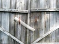 Close-up old wooden rickety gates. Rustic gate made of dry gray planks with rusty handles. Countryside scene. Fragment of closed