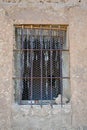 close up of an old wooden window with bars of iron blocking the access, in a wall of concrete, mud and stone in a closed abandoned Royalty Free Stock Photo