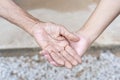 Close-up of old and young holding hands. Middle-aged mommy's wrinkled hands holding young daughters,