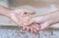 Close-up of old and young holding hands. Middle-aged mommy's wrinkled hands holding young daughters,