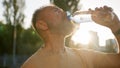 Close up older man drinking clear mineral water morning sun rays thirsty male drink pure aqua bottle city sunlight Royalty Free Stock Photo