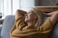 Close up older peaceful woman relaxing leaned on sofa Royalty Free Stock Photo