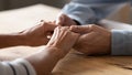 Close up older spouses holding hands on wooden table Royalty Free Stock Photo