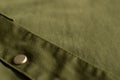 Close up of olive green military uniform fabric with metal button