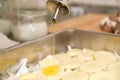 Close-up of olive oil being poured over sliced raw potatoes and onion