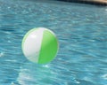 Close-up one bright green beach ball in swimming pool sunny day Royalty Free Stock Photo