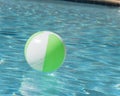 Close-up one bright green beach ball in swimming pool sunny day