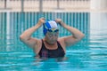 Close up of one mature woman fixing her goggles in a swimming pool alone - portrait of mature woman swimming and training or doing Royalty Free Stock Photo
