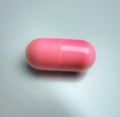 Close up of one pink pill laying on white background Royalty Free Stock Photo