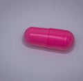 Close up of one pink pill laying on white background Royalty Free Stock Photo