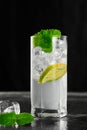 Close-up of one tall glass with a mojito cocktail on a dark background. Vertical shot from a low angle Royalty Free Stock Photo