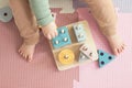 Toddler baby sitting on carpet playing with colorful wooden stacking toy Royalty Free Stock Photo