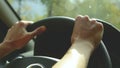 Close-up on open aperture. The girl drives a car on a country road. Women`s hands on the steering wheel