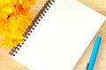 Close up open blank spiral note book and yellow flower on wood background Royalty Free Stock Photo
