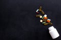 Close up of an open bottle of medicine and its lid. Several pills are lying on black desk. Pharmacology and medical Royalty Free Stock Photo