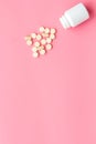 Close up of an open bottle of medicine and its lid. Several pills are lying on pink desk. Pharmacology and medical Royalty Free Stock Photo