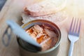 Close up of open canned tuna in red oil, fork and bread on wooden table, top view Royalty Free Stock Photo