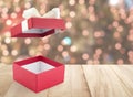 empty open red gift box with white ribbon bow on wooden counter top with blurred colorful small lights bokeh on christmas tree Royalty Free Stock Photo