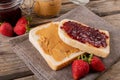 Close-up open face peanut butter and jelly sandwich on napkin with jars and strawberries at table Royalty Free Stock Photo