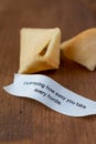 Close-up of open fortune cookie with message, on wooden table, vertically,