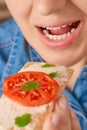 Close-up of the open mouth of a pretty Caucasian woman bringing a crispy bread with a curd spread to it. Front three-quarter view