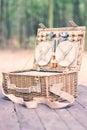 Close up of an open picnic basket over wooden table in the park. Vintage style.